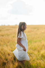 A beautiful girl is picking flowers in the forest on a glade.