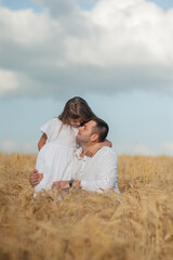 dad and daughter hug in a wheat field.Cute beautiful children.Family vacation.Happy family resting in summer park.Cheerful family picnicking in the park.Summertime and vacation concept.
