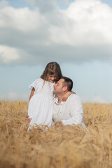 Dad and daughter hug in a wheat field.
