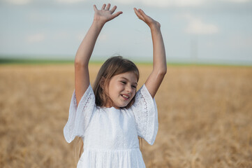 Happy child spends his childhood in the country, runs happily next to the wheat field.