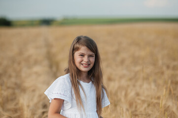 A very beautiful little girl.The child is smiling.Wheat field sunny day.