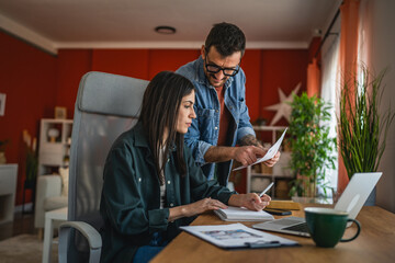 two colleagues work from home on laptop and clipboard on new project