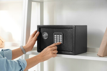Woman opening safe on shelf at home, closeup