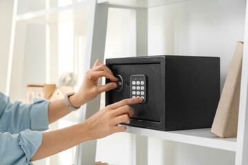 Woman opening safe on shelf at home, closeup
