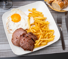 Picture of delicious fried pork with fried eggs and french fries at plate