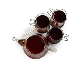 Glasses of aromatic tea in holders and teapot isolated on white, top view
