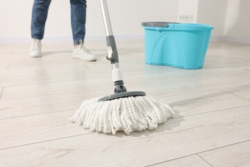 Woman cleaning floor with string mop indoors, closeup