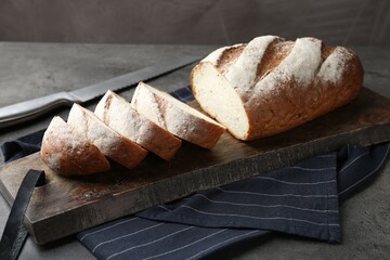 Cutting board with fresh bread on grey table