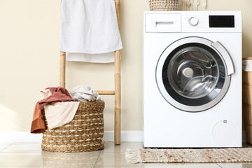 Basket with dirty clothes and washing machine in laundry room