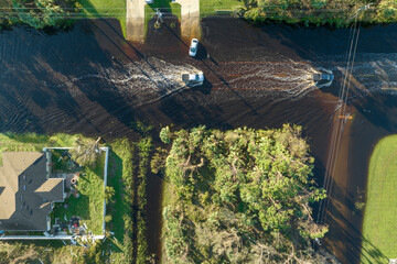 Hurricahe fainfall flooded Florida road with evacuating cars and surrounded with water houses in...