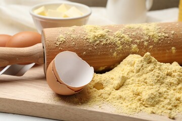 Rolling pin and different ingredients on table, closeup