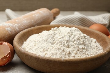 Rolling pin, flour and eggs on light grey background, closeup