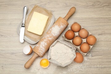 Rolling pin and different ingredients on light wooden table, flat lay