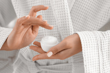 Young woman applying cream in bathroom, closeup