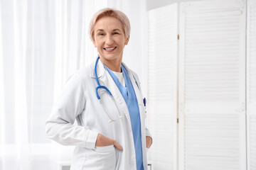 Happy mature female doctor with stethoscope in clinic