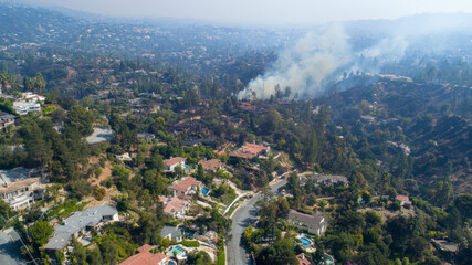 Fototapeta premium Aerial view of a hillside neighborhood with a wildfire in the background