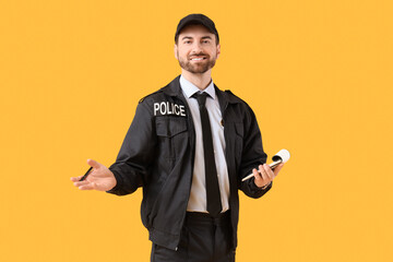Happy male police officer with notebook on yellow background