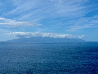 Obraz premium Seascape with La Gamora on the horizon, blue sea and sky and rocks