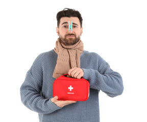 Ill young man with clothespin on his nose and first aid kit against white background. Stuffy nose...