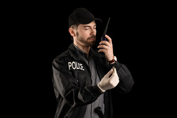 Male police officer with radio transmitter and bullet on black background