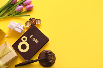 Beautiful tulip flowers with judge gavel, scales and law book on yellow background. International Women's Day celebration