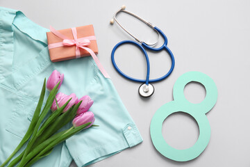 Tulip flowers with surgeon uniform, paper figure 8 and gift box on grey background. International Women's Day celebration