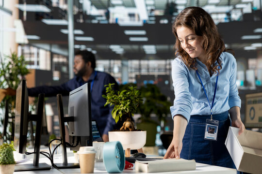 Hopeful female newbie installing her office supplies at her new workstation, feeling optimistic about the new beginning. Woman unpacking and settling in at her new corporate job. - Powered by Adobe