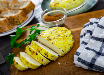 Cumin cheese with cut out segment on wooden board with sprig of rosemary and cumin in cafe