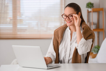 Beautiful young happy woman in new eyeglasses with laptop sitting at home