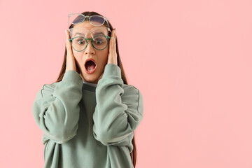 Beautiful young shocked woman in different new eyeglasses on pink background