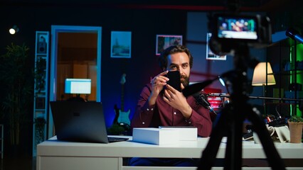 Tech guru using professional camera to film technology review of new cellphone, doing unboxing...