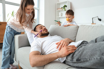 Obraz premium Little children painting their father's face while he sleeping at home. April fool's day prank