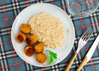 Portion of round albondigas meatballs with side dish of boiled oatmeal is served. Meatballs made according to traditional Spanish recipe from ground beef and spices, cumin, garlic, hot pepper