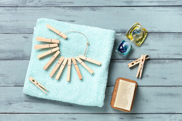 Clothespins with clean towel, soap and gel capsules on wooden blue background