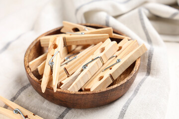 Bowl of clothespins with fabric on white wooden background