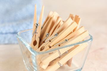 Bowl of wooden clothespins and clean towel on white background