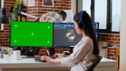 Software developer works in a modern office with green screen and dual monitors. Home workspace emphasizes industrial innovation and expertise in manufacturing design. Camera B.