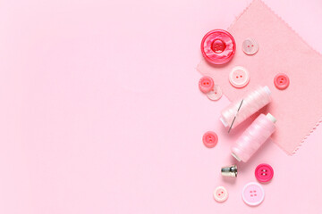 Different colorful buttons with thread spools and fabric sample on pink background