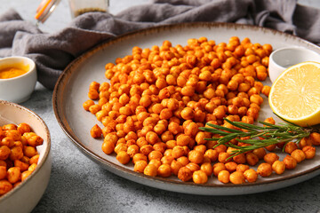 Plate with tasty fried chickpeas, lemon and rosemary on grey background, closeup