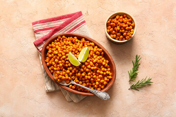 Bowls of tasty fried chickpeas with lime and rosemary on beige background