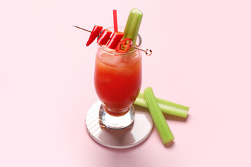 Glass of bloody mary cocktail with chili pepper and celery on pink background