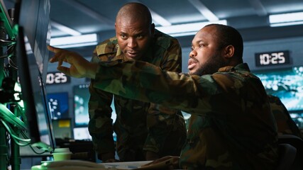 Air force officer and colleague performing tactical level surveillance in command post. Team of military specialists doing brainstorming, using radar equipment to look at assault zones, camera A