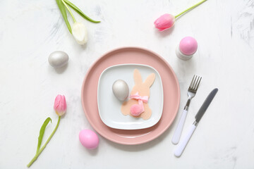 Beautiful table setting with Easter eggs, bunny and tulip flowers on white background