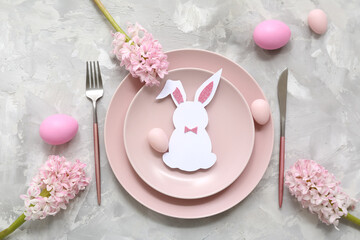 Stylish table setting with pink Easter eggs, paper bunny and beautiful flowers on grey background