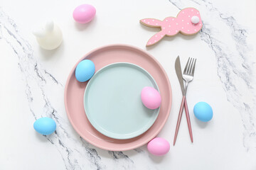 Beautiful table setting with Easter eggs, candle and bunny on white background
