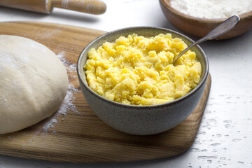 Mashed potatoes with fried onions and dough for kreplach or dumplings preparation on a gray background