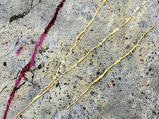 Obraz premium Close-up of a textured concrete surface with gold and red paint splashes and drips.
