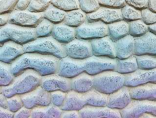 Close-up view of a textured stone wall with a blue and purple color scheme.