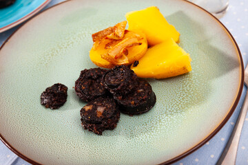 Traditional Spanish blood sausage slices with rice served with baked potatoes..