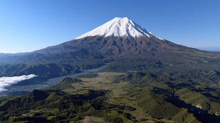 Fototapeta premium Majestic view of snow-capped mountain towering over lush green valleys and distant clouds